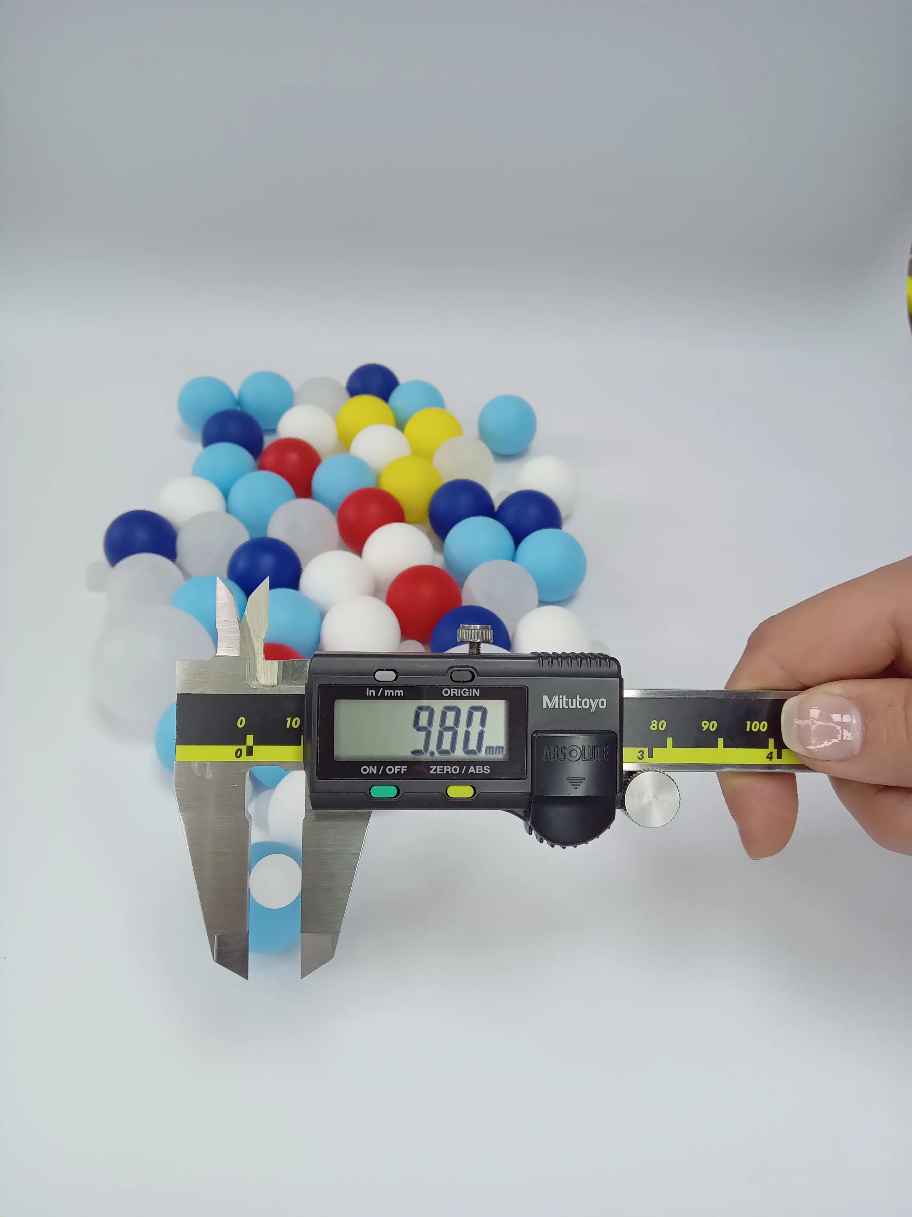 Bolilla plástica de 9.80mm (0.386 pulgadas) siendo medida con un calibrador digital para aplicaciones cosméticas pequeñas